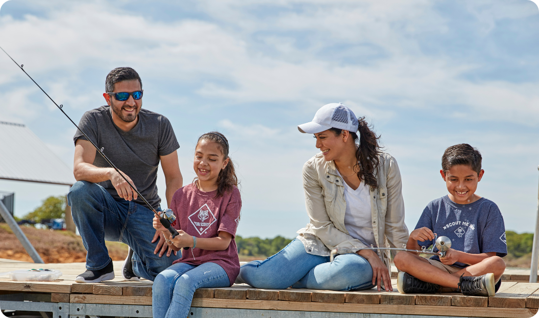 Parents and cub scouts sitting on dock smiling
